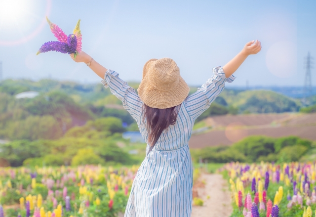 生きづらさを解消したイメージの花畑で両腕を広げる女性